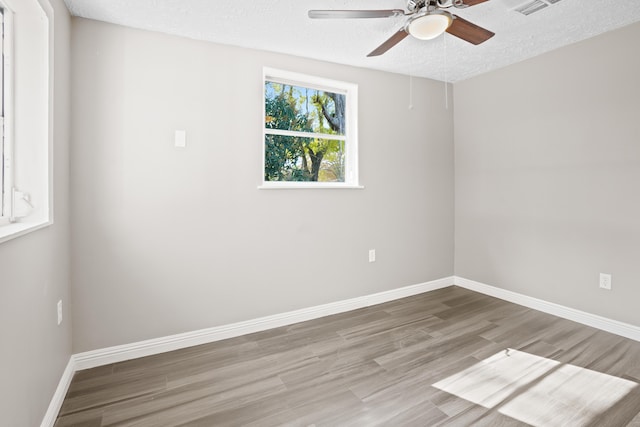 unfurnished room with ceiling fan, wood-type flooring, and a textured ceiling