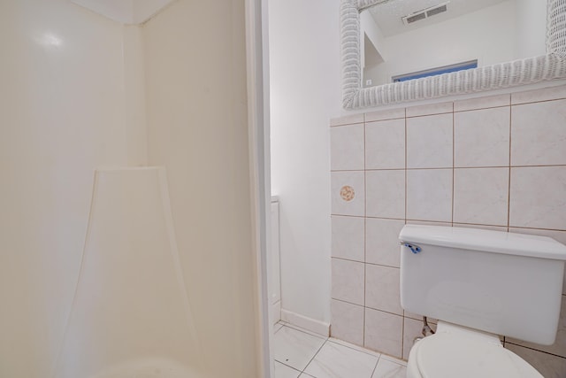 bathroom with toilet, visible vents, and tile walls