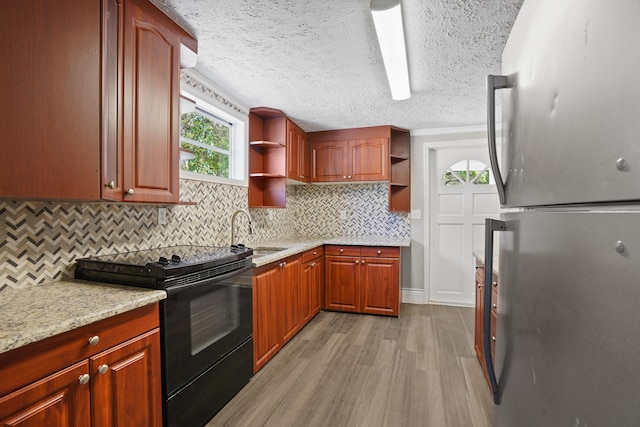 kitchen featuring black electric range oven, open shelves, light wood-type flooring, a sink, and freestanding refrigerator