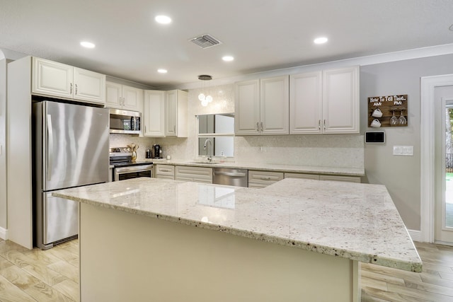 kitchen featuring hanging light fixtures, stainless steel appliances, white cabinets, and light stone countertops