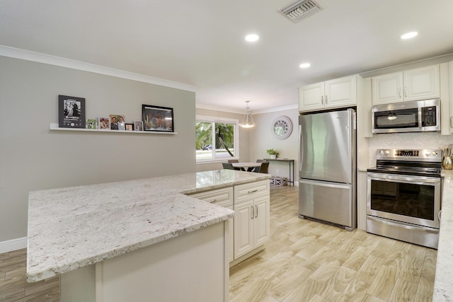 kitchen with decorative light fixtures, ornamental molding, white cabinets, and appliances with stainless steel finishes