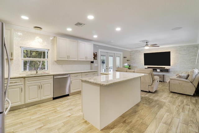 kitchen featuring a kitchen island, decorative light fixtures, sink, light stone counters, and stainless steel appliances