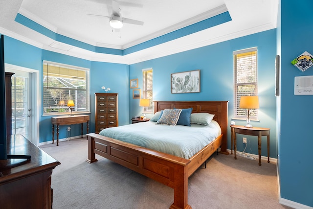 carpeted bedroom with crown molding, a tray ceiling, and ceiling fan