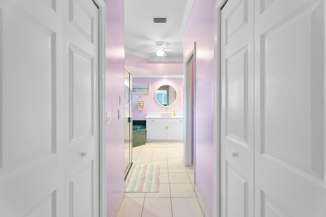 corridor featuring ornamental molding and light tile patterned floors