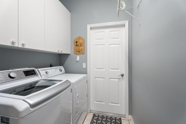 clothes washing area with separate washer and dryer, light tile patterned floors, and cabinets