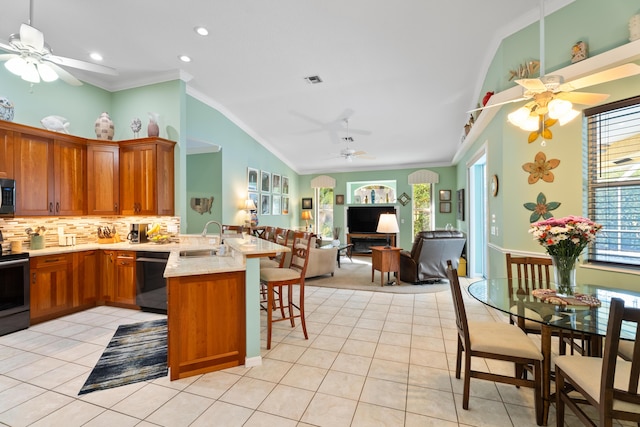 kitchen featuring sink, a breakfast bar area, appliances with stainless steel finishes, light tile patterned flooring, and kitchen peninsula