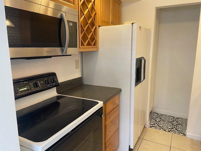 kitchen featuring range with electric stovetop, white refrigerator with ice dispenser, and light tile patterned flooring