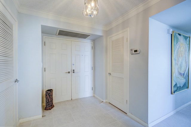 hall with a textured ceiling, a chandelier, visible vents, baseboards, and ornamental molding