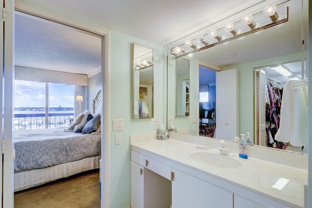 bathroom with connected bathroom, vanity, and a spacious closet