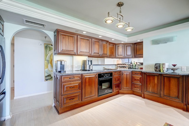 kitchen with stone countertops, visible vents, brown cabinets, decorative light fixtures, and oven