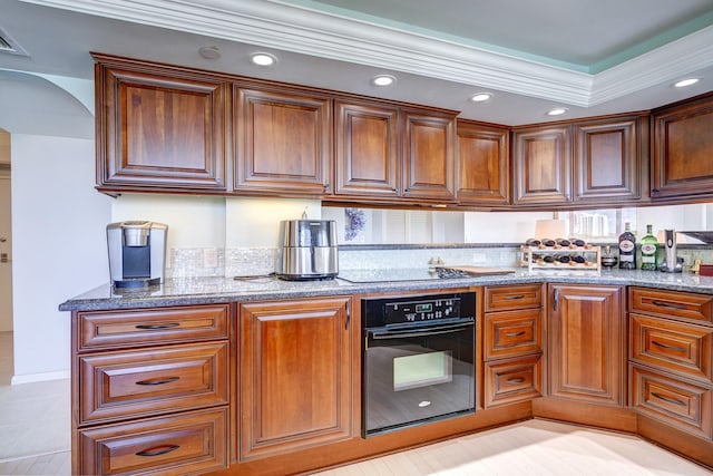 kitchen featuring black appliances, stone counters, arched walkways, and brown cabinetry