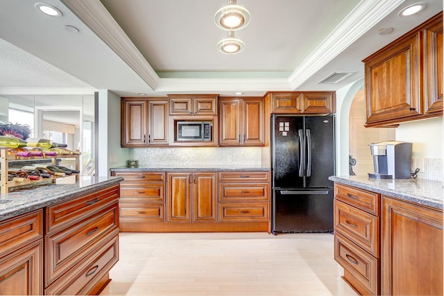 kitchen featuring ornamental molding, freestanding refrigerator, a raised ceiling, and light stone countertops