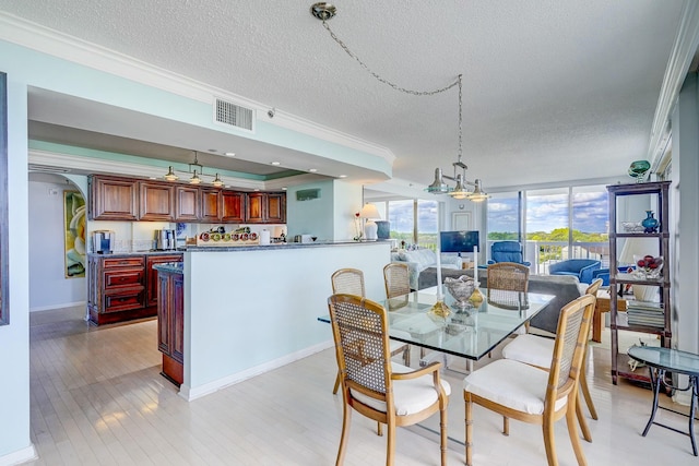 dining area featuring light wood finished floors, a textured ceiling, visible vents, and crown molding