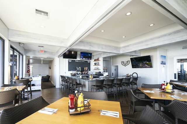 dining space with dark wood-style floors, a community bar, visible vents, and recessed lighting