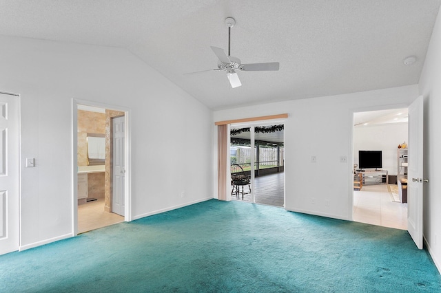 carpeted empty room with vaulted ceiling, ceiling fan, and a textured ceiling