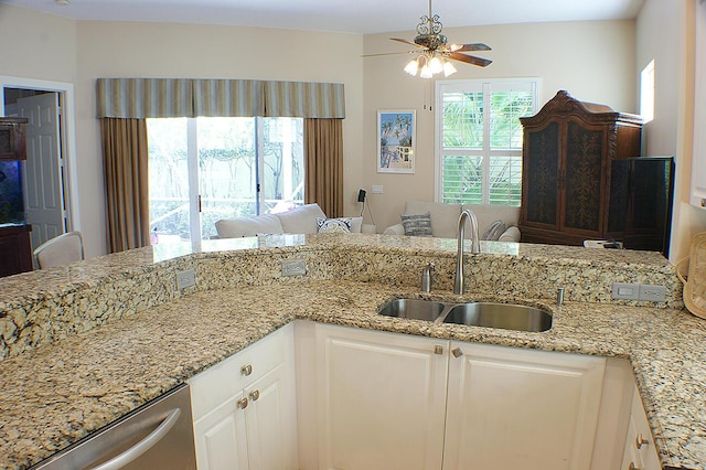 kitchen with sink, ceiling fan, dishwasher, light stone countertops, and white cabinets