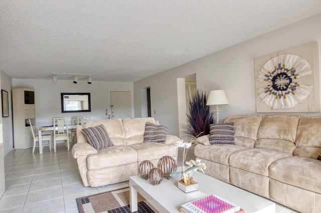 tiled living room featuring rail lighting and a textured ceiling