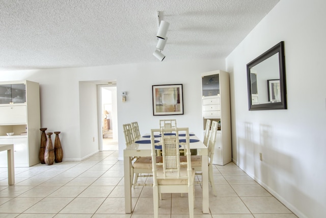 tiled dining space featuring track lighting and a textured ceiling