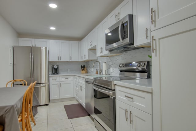 kitchen featuring light tile patterned flooring, appliances with stainless steel finishes, tasteful backsplash, white cabinetry, and sink