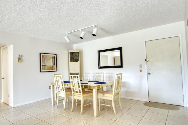 tiled dining room with track lighting and a textured ceiling