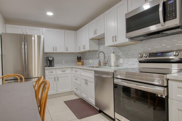 kitchen with sink, light tile patterned floors, appliances with stainless steel finishes, tasteful backsplash, and white cabinets