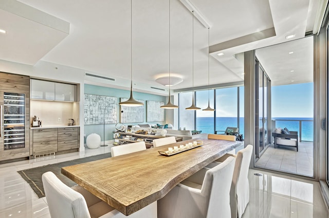 dining area featuring beverage cooler, expansive windows, and a water view