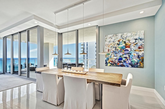 tiled dining room featuring a wall of windows and a water view