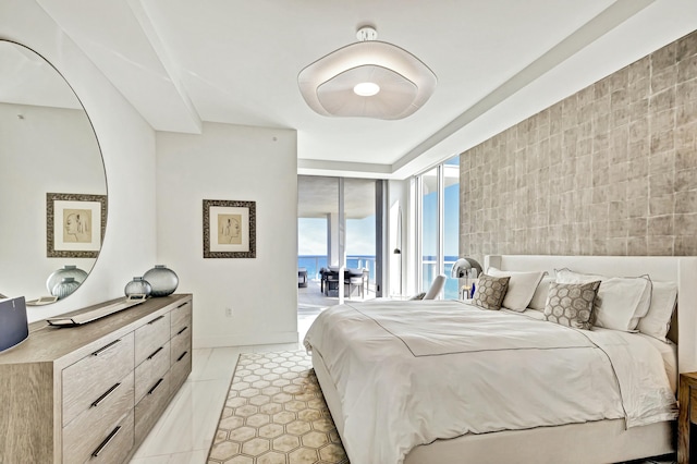 tiled bedroom with access to outside, floor to ceiling windows, and a water view