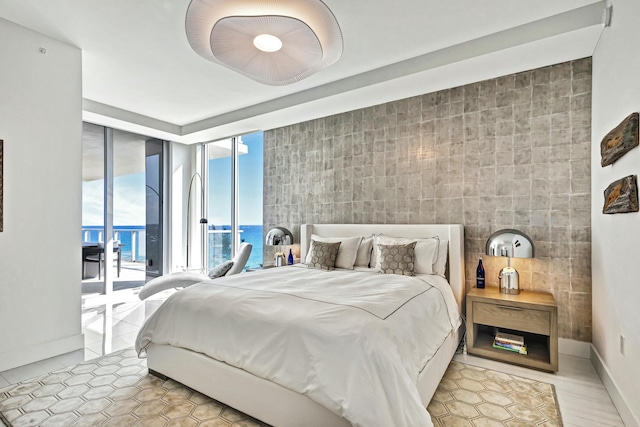 bedroom featuring a wall of windows, access to outside, light tile patterned floors, ceiling fan, and a water view