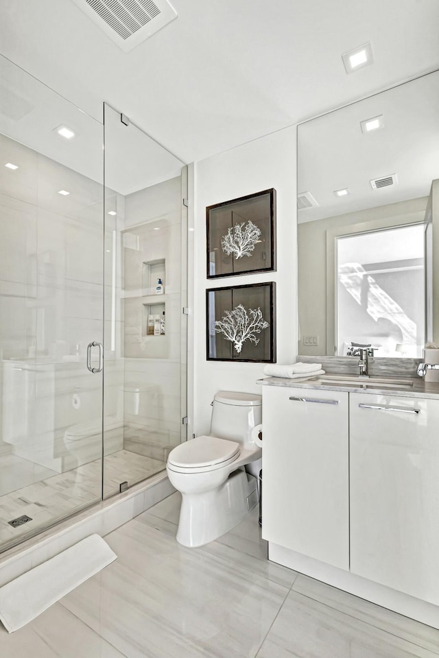 bathroom featuring vanity, a shower with door, and toilet