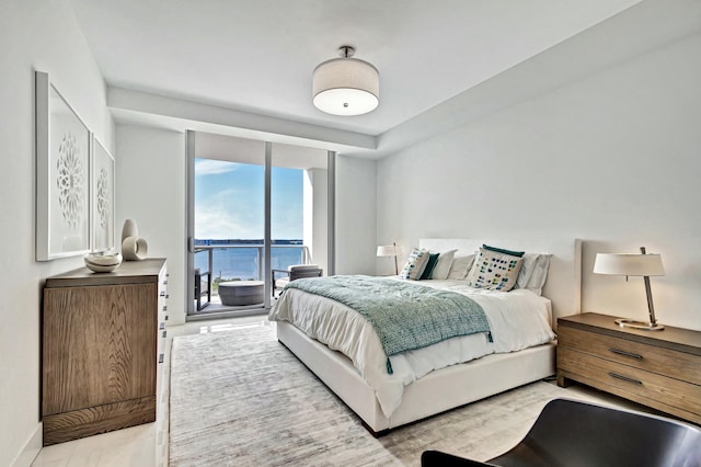 bedroom with floor to ceiling windows, a water view, and access to exterior