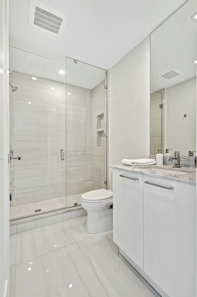 bathroom featuring vanity, toilet, and a shower with door