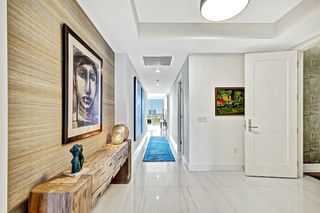 hallway with light tile patterned floors and a tray ceiling