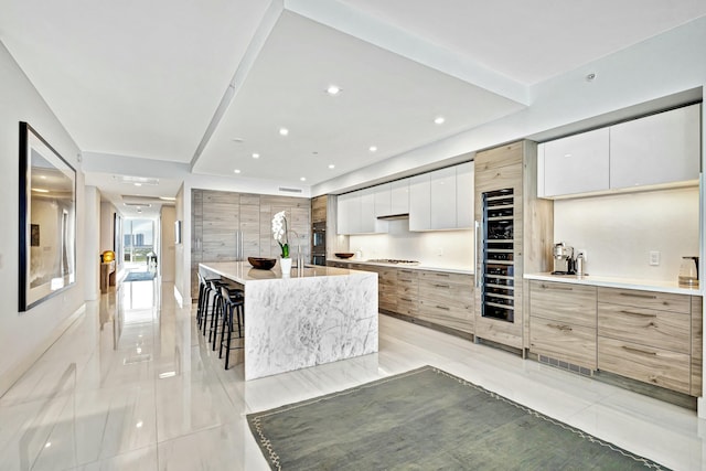 kitchen with a breakfast bar, white cabinets, stainless steel gas cooktop, and a spacious island