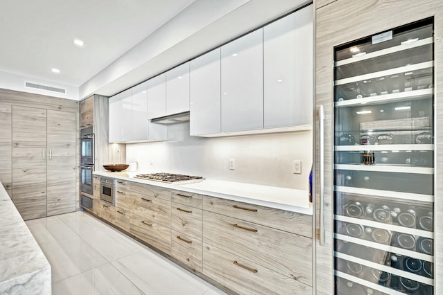 kitchen featuring white cabinetry, appliances with stainless steel finishes, light tile patterned flooring, and beverage cooler