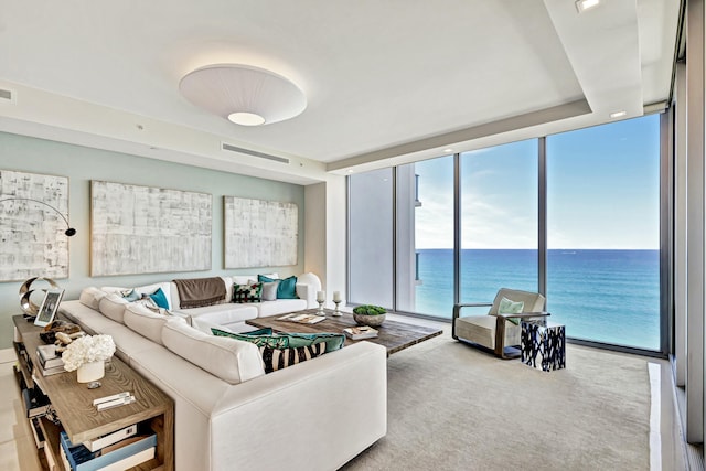 living room featuring expansive windows, a water view, and light colored carpet