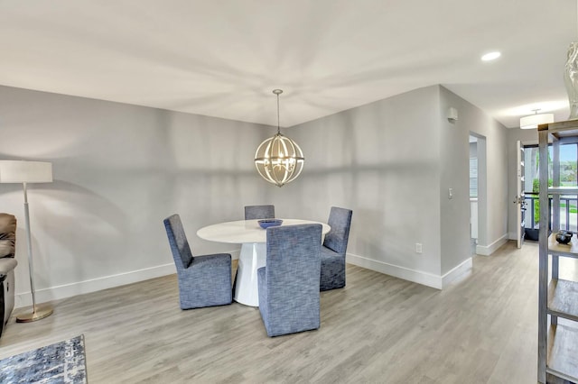 dining room with light hardwood / wood-style floors and a notable chandelier