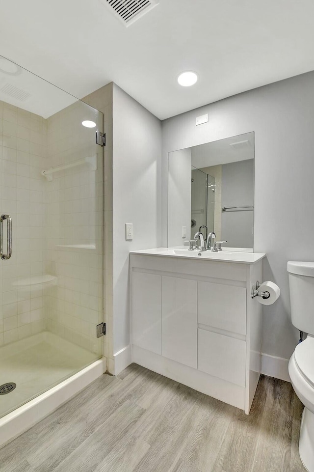 bathroom with hardwood / wood-style flooring, vanity, toilet, and walk in shower