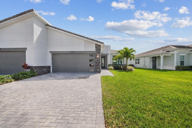 view of front of home with stone siding, an attached garage, decorative driveway, a front yard, and stucco siding