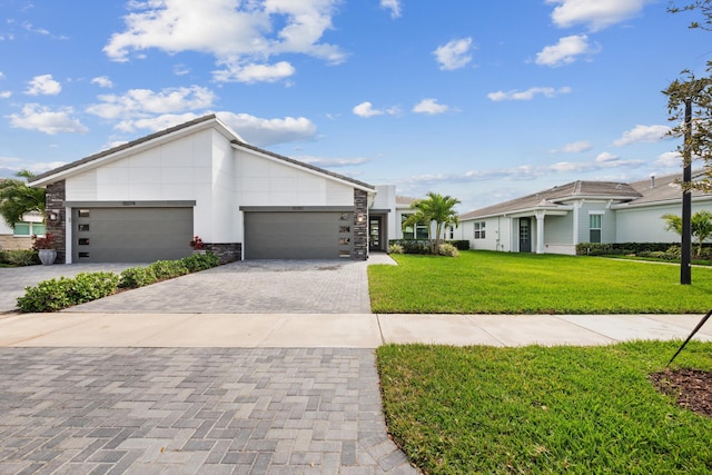 view of front facade featuring a garage, stone siding, decorative driveway, a front yard, and stucco siding