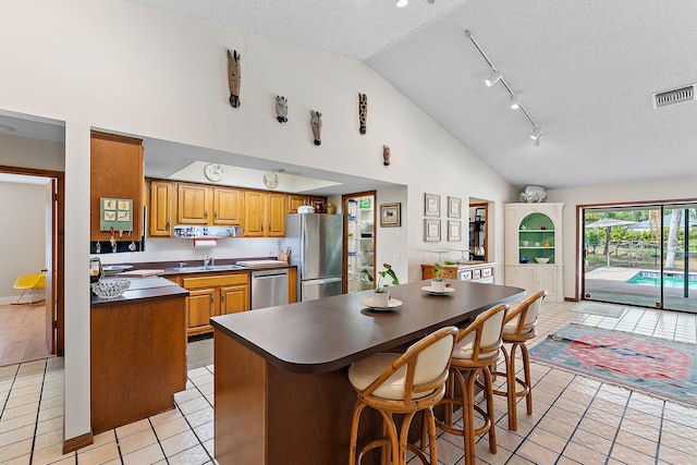 kitchen featuring sink, a breakfast bar area, appliances with stainless steel finishes, a center island, and a textured ceiling