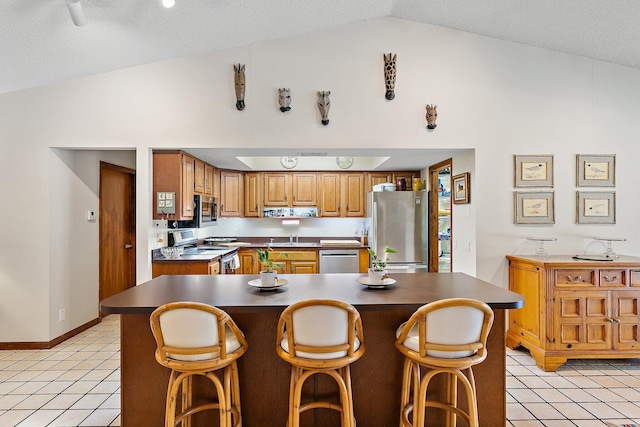 kitchen featuring light tile patterned floors, sink, appliances with stainless steel finishes, a kitchen breakfast bar, and a kitchen island