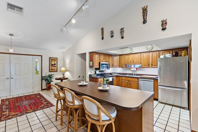 kitchen with light tile patterned flooring, appliances with stainless steel finishes, lofted ceiling, sink, and a textured ceiling