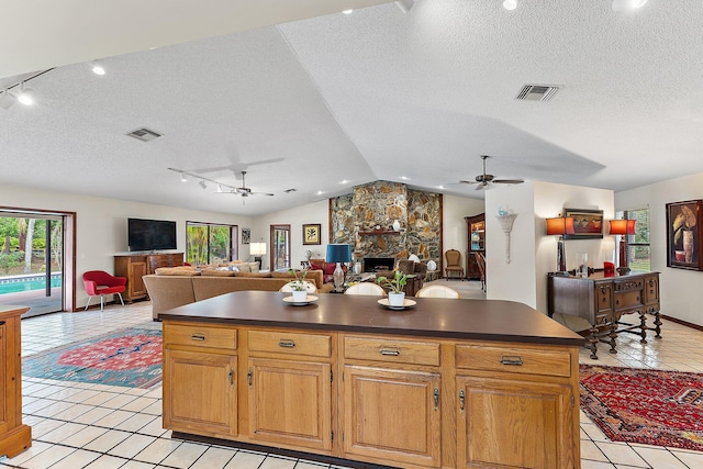 kitchen with vaulted ceiling, a center island, a fireplace, and a textured ceiling