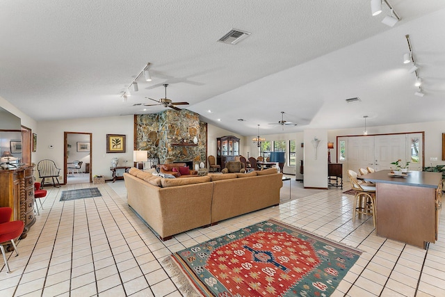 tiled living room featuring ceiling fan, lofted ceiling, a fireplace, and a textured ceiling