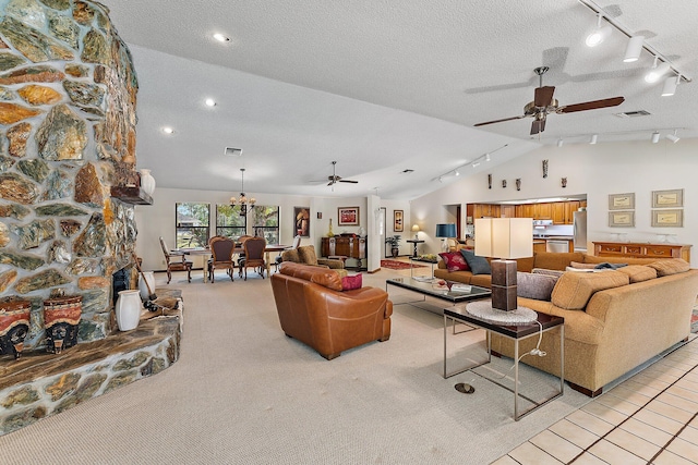 carpeted living room featuring lofted ceiling, ceiling fan with notable chandelier, a textured ceiling, and a fireplace