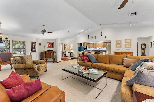 living room featuring ceiling fan with notable chandelier, vaulted ceiling, light colored carpet, and a textured ceiling