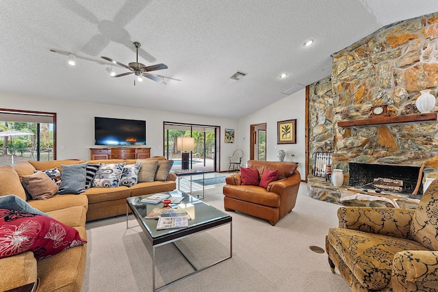 carpeted living room with ceiling fan, lofted ceiling, a fireplace, and a textured ceiling