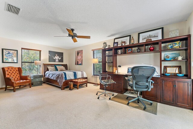 bedroom with ceiling fan, light colored carpet, and a textured ceiling