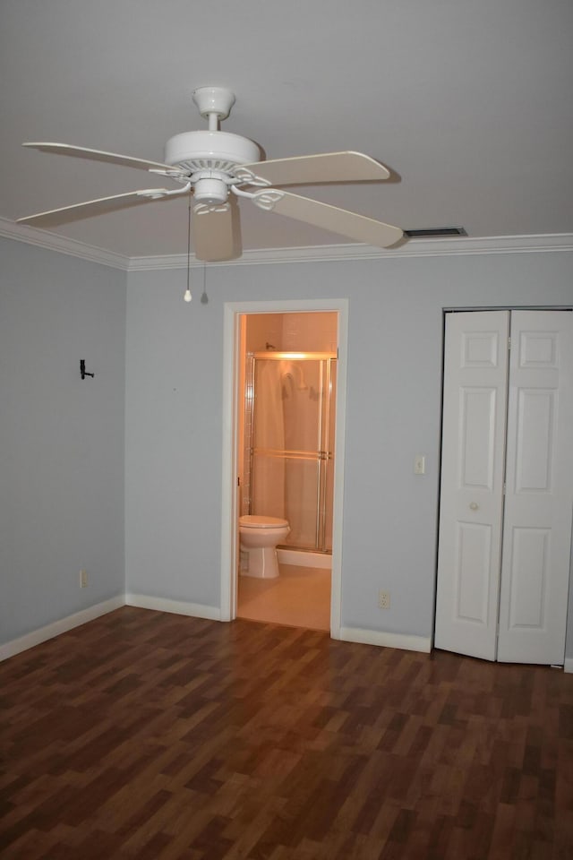 unfurnished bedroom featuring crown molding, a closet, dark hardwood / wood-style flooring, and ensuite bath